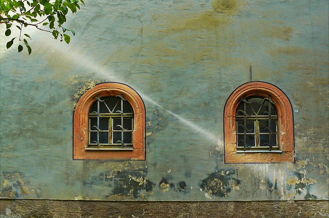 Stena domu s dvoma oknami, na ktorú dopadajú slnečné lúče