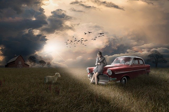 Rozprávkový obrázok červeného auta na lúke, sedí na ňom žena a vedľa ovca.jpg
