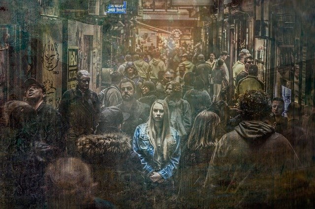 Vystresovaná žena v modrej bunde stojí uprostred hustého davu ľudí.jpg